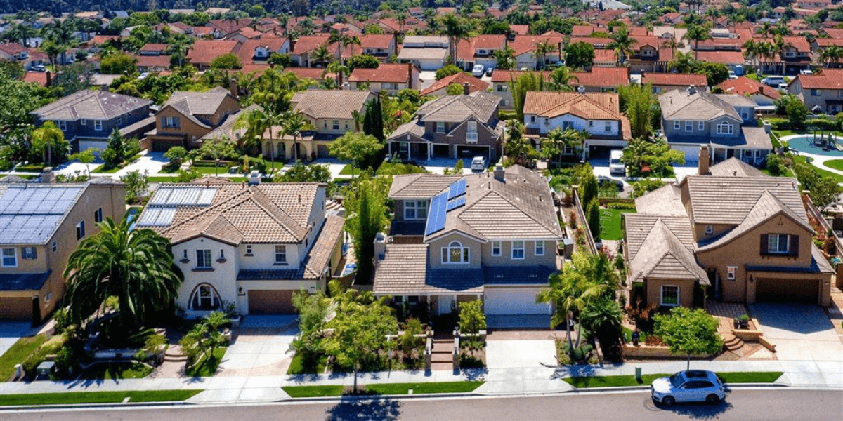 Aerial view of suburban neighborhood with houses, palm trees, and solar panels