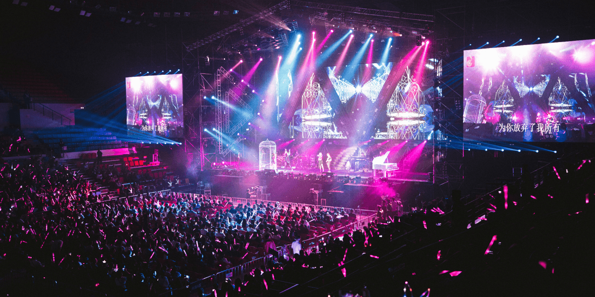 A vibrant concert scene with bright lights, a large audience, and performers on stage