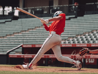 Baseball player swings at a pitch during an MLB game as the catcher reaches for the ball behind home plate.