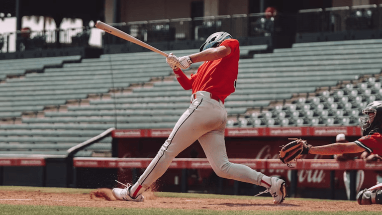 Baseball player swings at a pitch during an MLB game as the catcher reaches for the ball behind home plate.