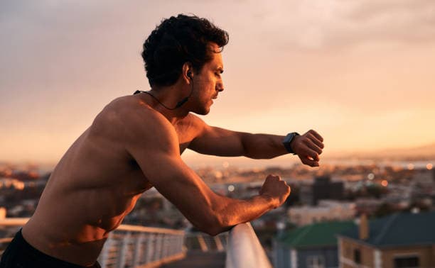 Shot of a young man checking the time during a workout in the city