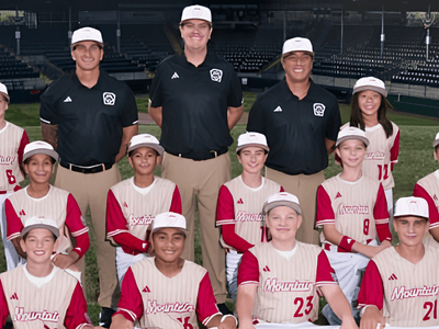 Youth baseball team and coaches posed on the field wearing matching uniforms and caps