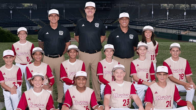 Youth baseball team and coaches posed on the field wearing matching uniforms and caps