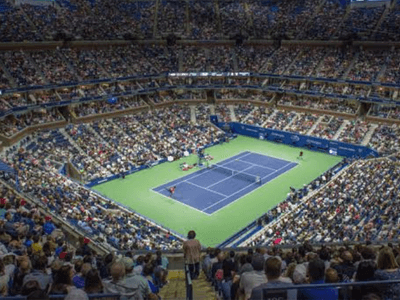 A packed tennis stadium filled with fans watching a match on an outdoor court