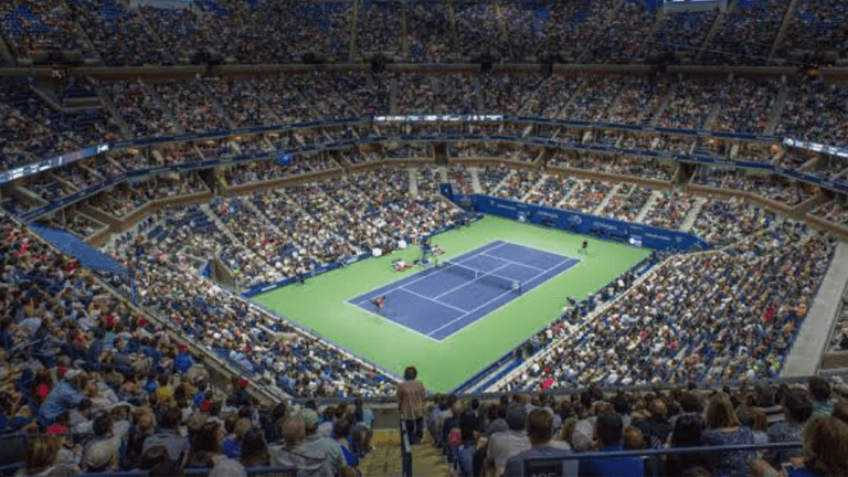 A packed tennis stadium filled with fans watching a match on an outdoor court