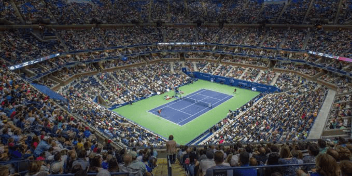 A packed tennis stadium filled with fans watching a match on an outdoor court