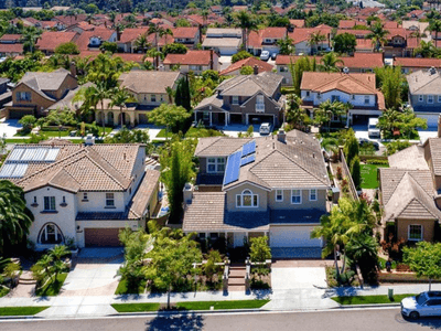 Aerial view of suburban neighborhood with houses, palm trees, and solar panels