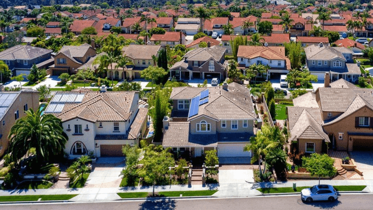 Aerial view of suburban neighborhood with houses, palm trees, and solar panels