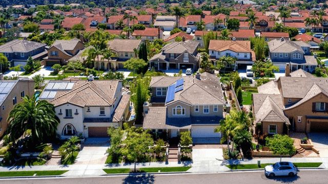 Aerial view of suburban neighborhood with houses, palm trees, and solar panels