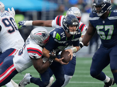 Seahawks quarterback being tackled by Patriots players during an NFL game action shot