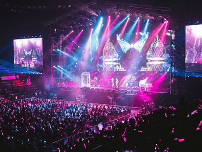 A vibrant concert scene with bright lights, a large audience, and performers on stage