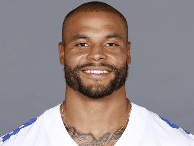 Smiling athlete wearing a football jersey, with a short beard and a gold chain