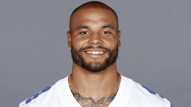 Smiling athlete wearing a football jersey, with a short beard and a gold chain