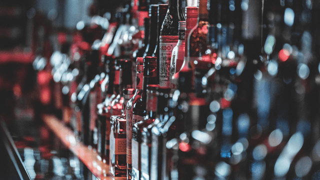 A blurred bar shelf filled with various bottles of liquor and spirits