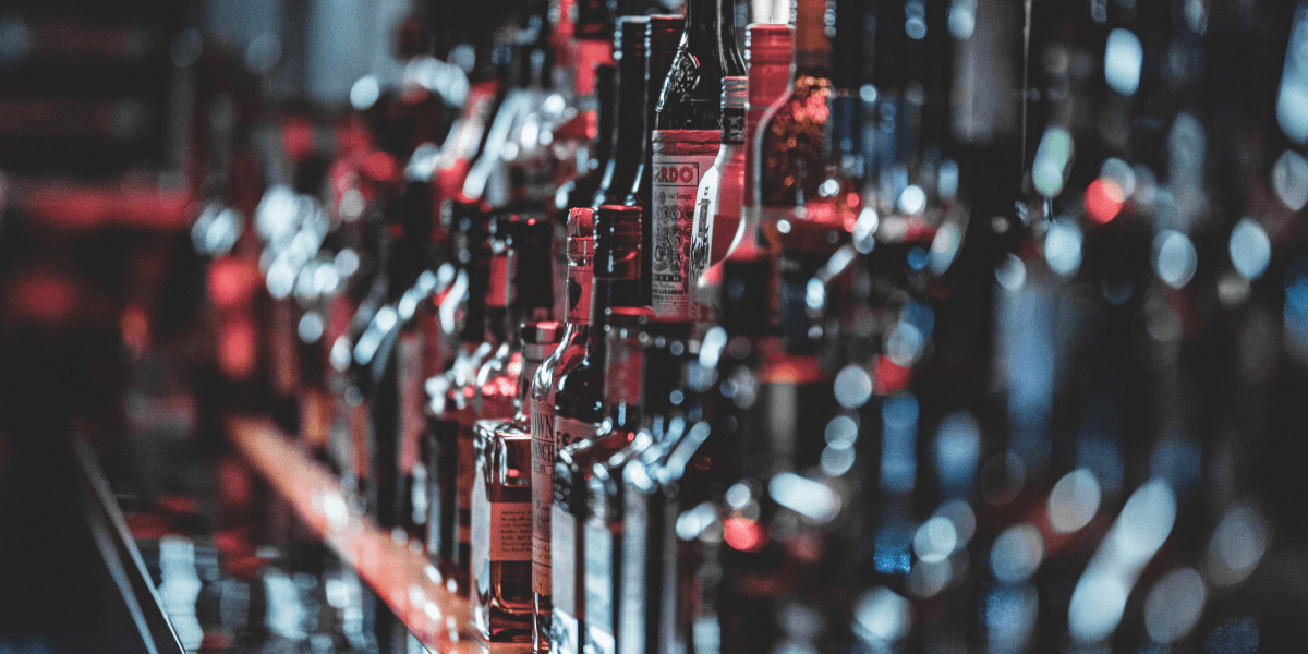 A blurred bar shelf filled with various bottles of liquor and spirits