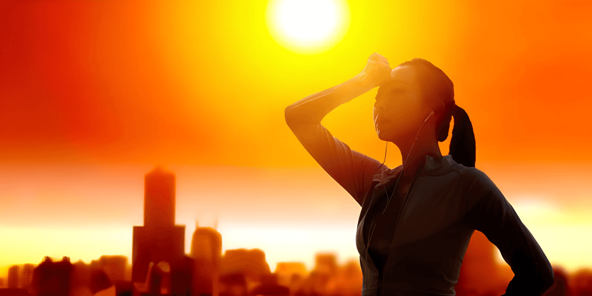 Silhouetted woman with earbuds stands against a vibrant sunset over a city skyline