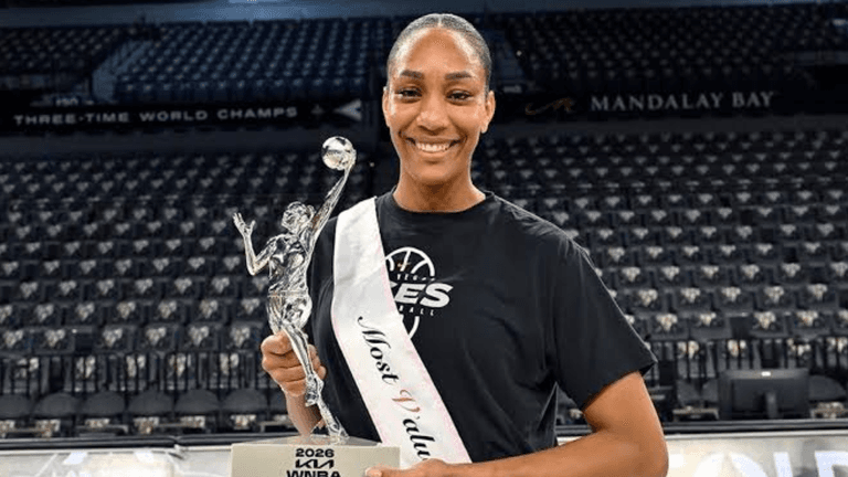 A female basketball player smiling proudly with a trophy and sash in her uniform